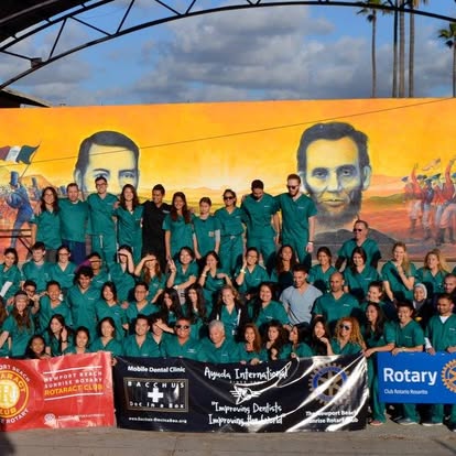 Ayuda International volunteers in green scrubs in front of a mural
