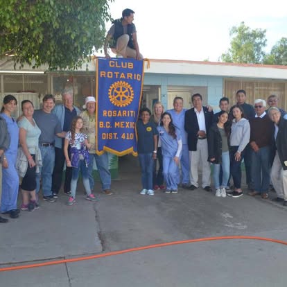 Volunteers with the Club Rotario Rosarito banner outside a school