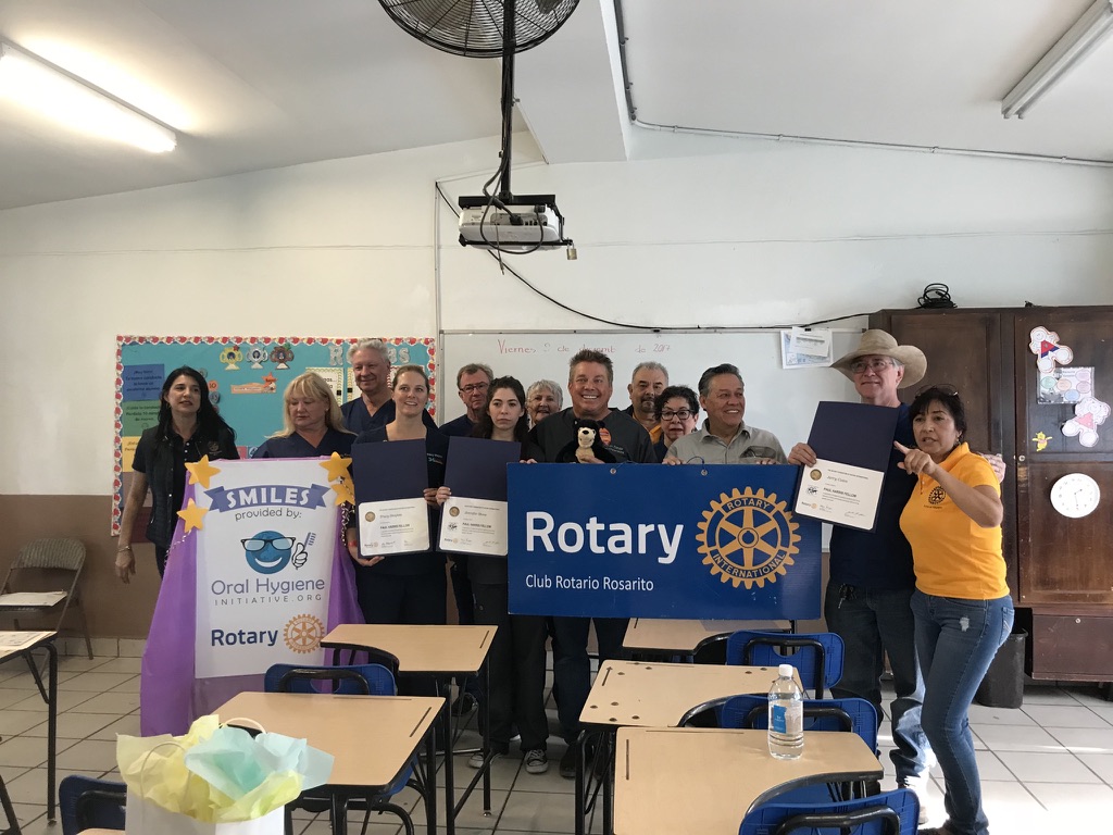 Rotary volunteers with certificates and the Smiles banner in a Rosarito classroom